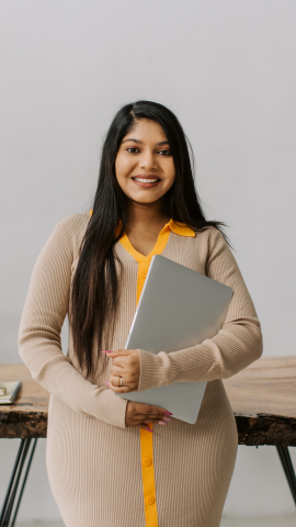 A women that appears of be of Asian decent holding a laptop