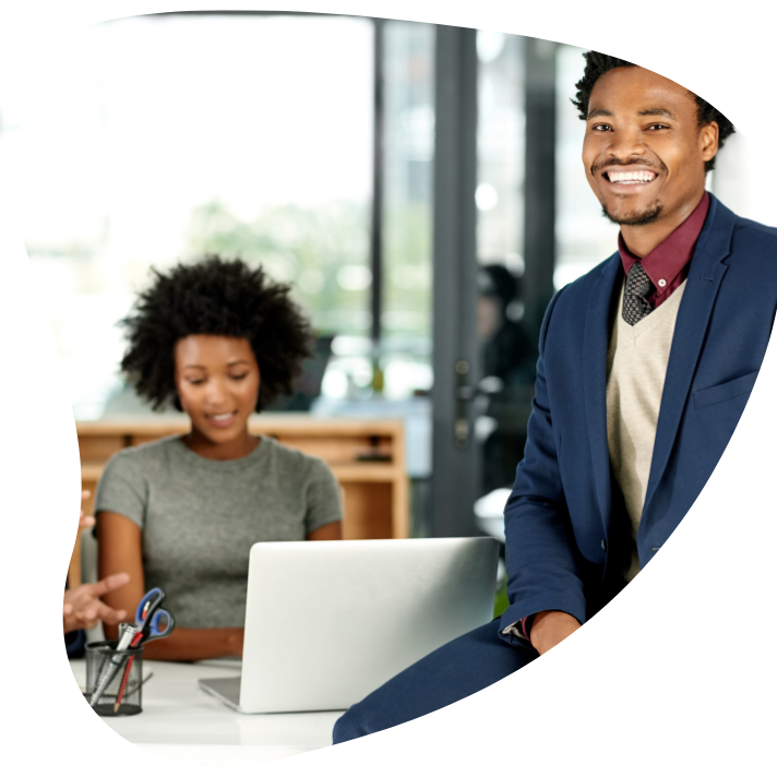 Guy sitting on desk while 2 others work
